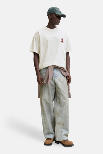 Wit T-shirt van ORIGINALS BY JACK & JONES, met een kleine rode print op de borst, gedragen met wijde jeans en een geruit overhemd om de taille.