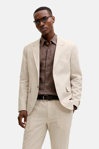 Blazer en lin écru de PREMIUM by JACK & JONES, porté par un homme avec une chemise marron, un pantalon assorti et des chaussures foncées.