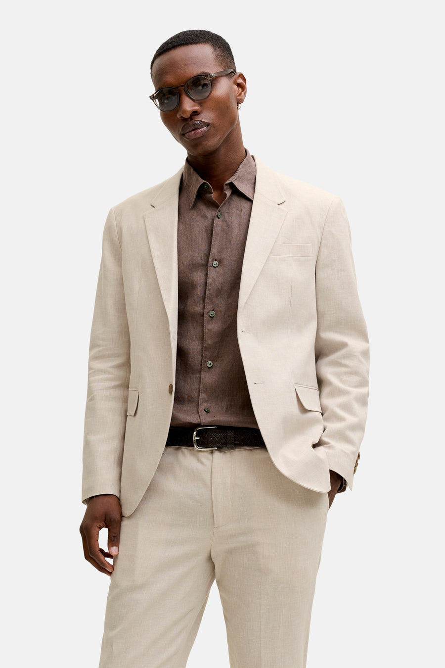 Blazer en lin écru de PREMIUM by JACK & JONES, porté par un homme avec une chemise marron, un pantalon assorti et des chaussures foncées.
