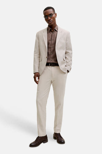 Ecru kostuumbroek van PREMIUM by JACK & JONES, gecombineerd met een bruin overhemd, zwarte riem en bruine leren schoenen.