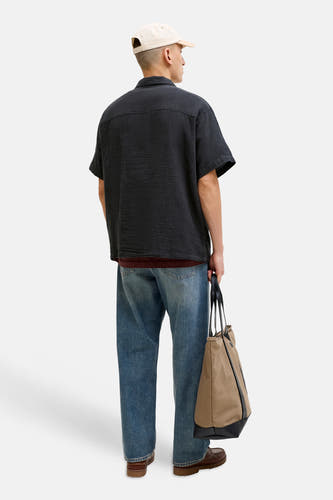 Chemise noire à manches courtes de ORIGINALS BY JACK & JONES, avec une texture froissée et portée avec un jean et un sac.