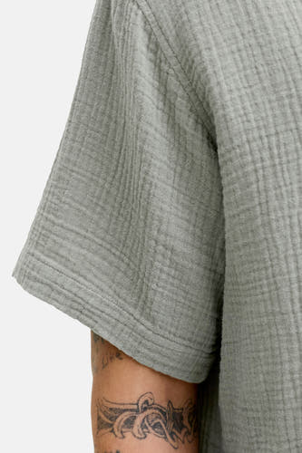 Chemise verte à manches courtes de ORIGINALS BY JACK & JONES, avec une texture plissée et un tatouage visible.