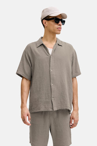 Chemise marron à manches courtes Originals by Jack & Jones, avec une texture granuleuse, portée avec une casquette, des lunettes de soleil et un short.