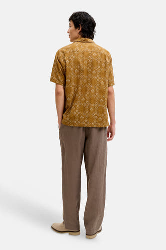 Chemise jaune à manches courtes de PREMIUM by JACK & JONES avec motif floral diagonal blanc, texturé, porté par un mannequin avec un pantalon marron et des chaussures beiges.