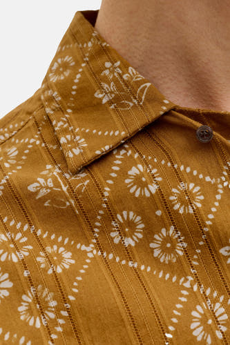 Chemise jaune de PREMIUM by JACK & JONES avec motif à fleurs et pois blancs, texture rayée et un bouton foncé, gros plan.