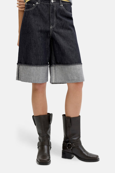 Short en jean bleu marine de JJXX, avec ourlet retroussé, combiné avec un polo gris rayé et des bottes marron.