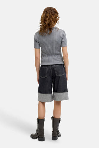 Short en jean bleu marine de JJXX, avec surpiqûres blanches et un large ourlet retroussé, porté avec des bottes en cuir marron.