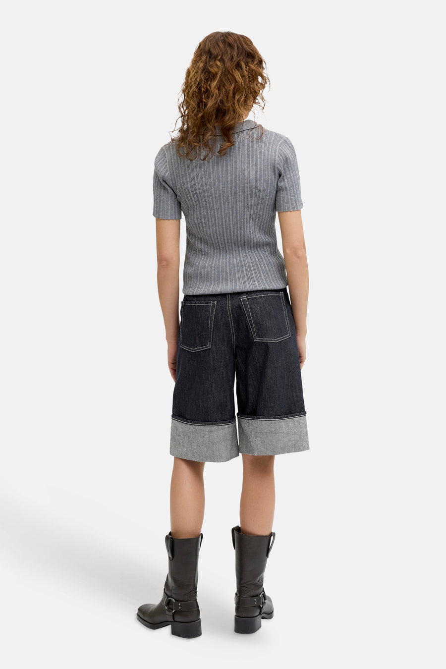 Short en jean bleu marine de JJXX, avec surpiqûres blanches et un large ourlet retroussé, porté avec des bottes en cuir marron.