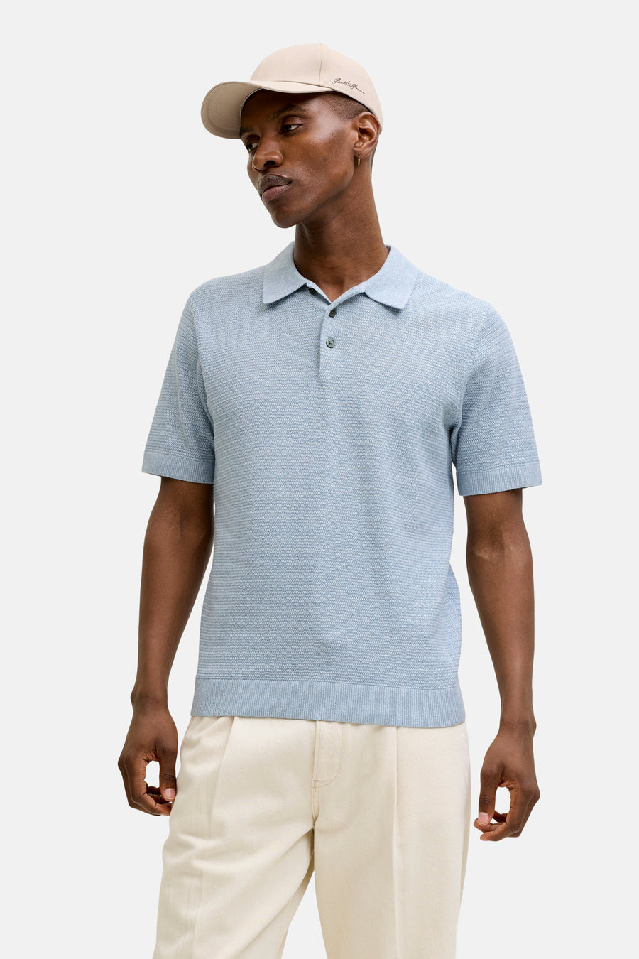 Polo bleu à manches courtes de PREMIUM BLUE by JACK & JONES, porté avec un pantalon crème et des chaussures marron.