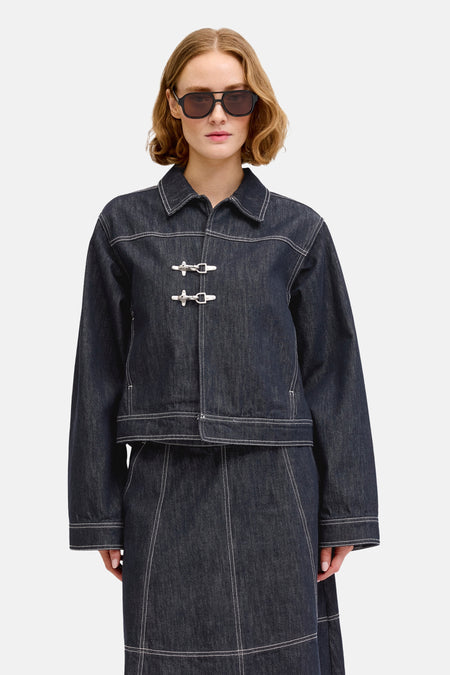 Veste en jean bleu foncé de JJXX, avec fermetures argentées et coutures blanches, portée avec une longue jupe assortie et des ballerines marron.
