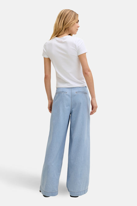 Jean en denim bleu clair coupe large de JJXX, avec jambes larges, vu de dos avec un t-shirt blanc.