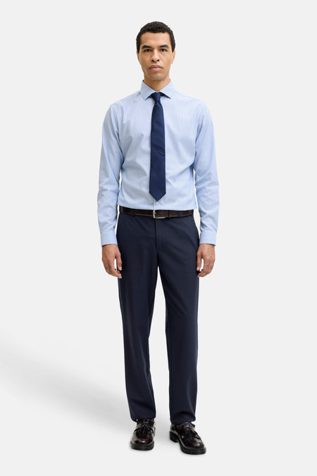 Blauwe broek van JACK & JONES JEANS INTELLIGENCE, gecombineerd met een gestreept overhemd, een stropdas en leren schoenen.