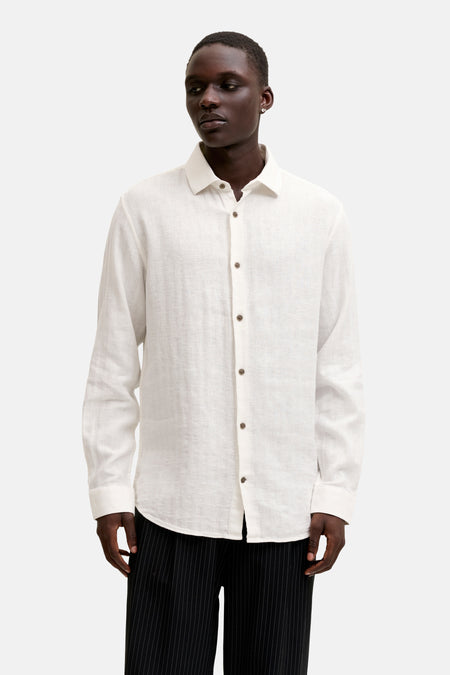 Chemise blanche aspect lin à manches longues de PREMIUM by JACK & JONES, portée avec un pantalon noir à fines rayures et des mocassins marron foncé.