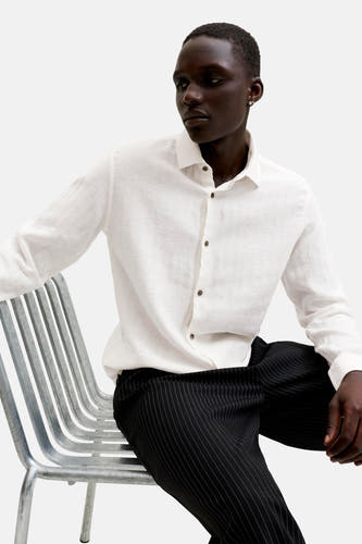 Chemise blanche à manches longues et boutons marron de PREMIUM by JACK & JONES, portée par un homme.