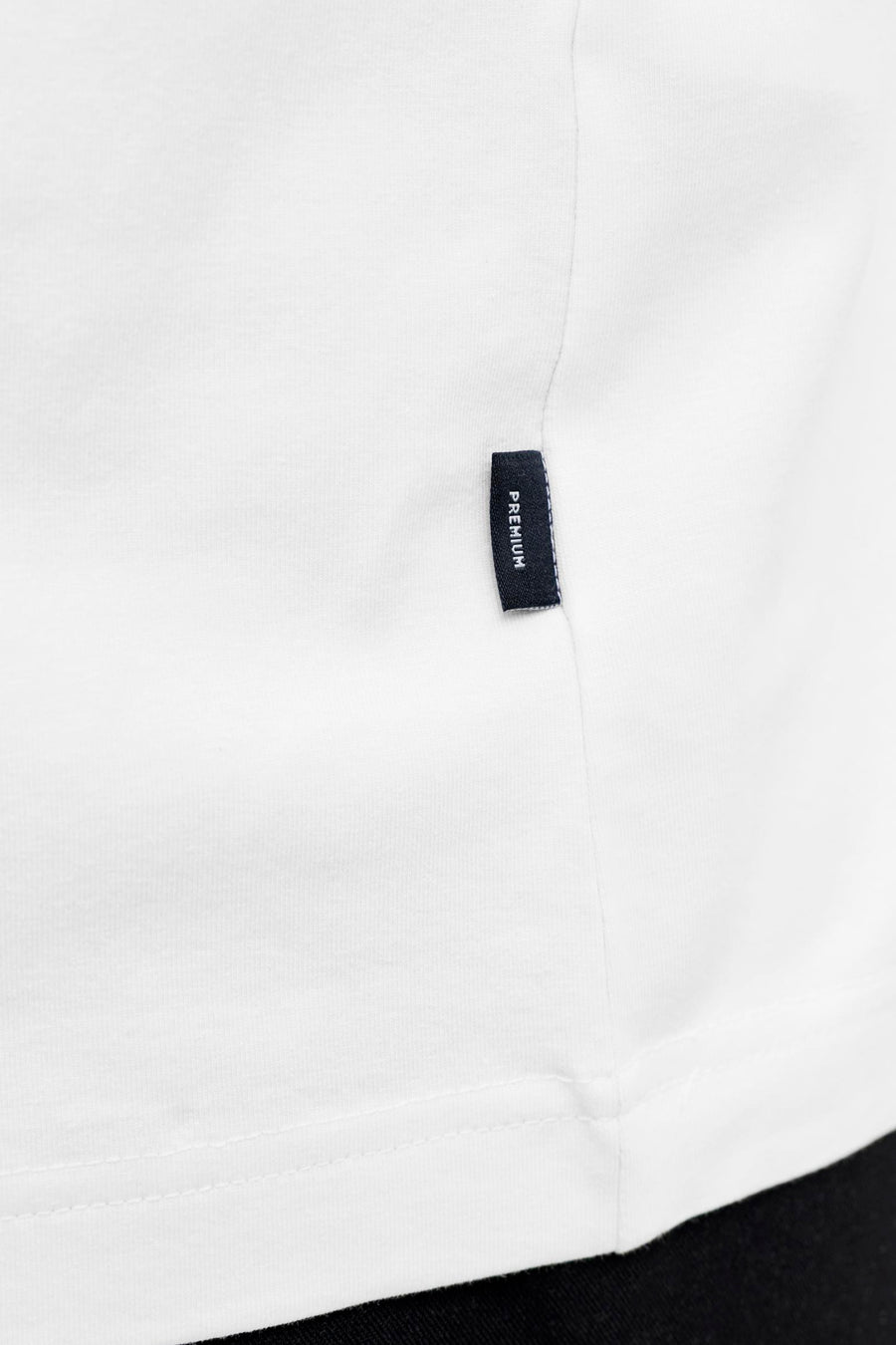 T-shirt blanc à manches courtes de PREMIUM by JACK & JONES, gros plan sur l'ourlet avec une petite étiquette.