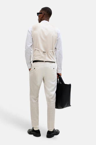 Gilet écru de PREMIUM by JACK & JONES, avec ceinture réglable à l'arrière, porté sur une chemise blanche et un pantalon clair.