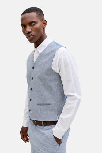 Gilet bleu de PREMIUM by JACK & JONES, avec fermeture boutonnée et une subtile poche poitrine, porté sur une chemise blanche.
