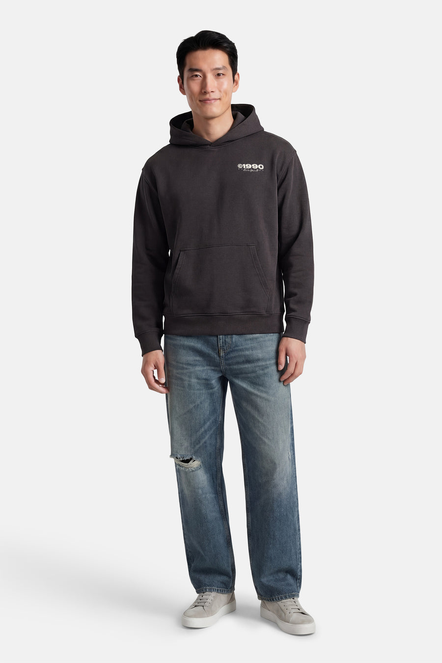 Sweat-shirt à capuche gris de CORE BY JACK & JONES, avec poche kangourou, combiné avec un jean bleu et des baskets grises.