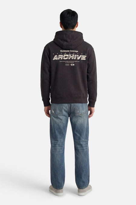 Grijze sweater met kap van CORE BY JACK & JONES, met print op de rug, gecombineerd met blauwe jeans en grijze schoenen.