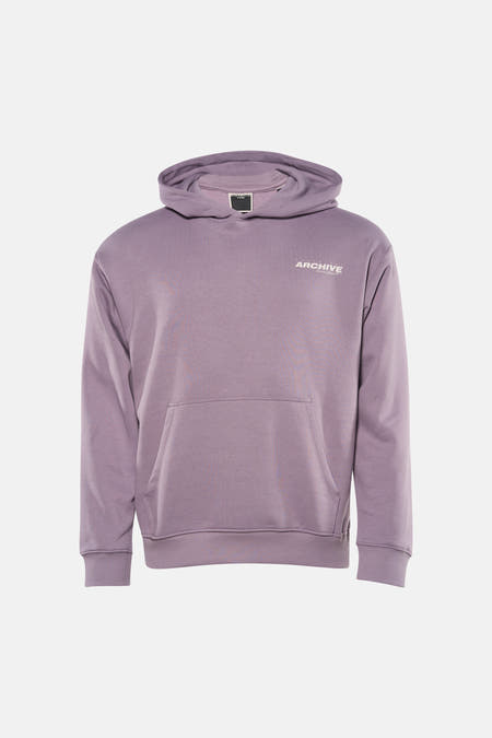 Sweat à capuche violet de CORE BY JACK & JONES, avec poche kangourou et porté avec un jean noir et des baskets beiges.