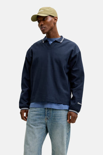 Pull bleu à col rond de ORIGINALS BY JACK & JONES, porté avec une veste en cuir, un jean et une casquette.