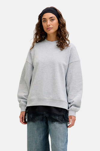 Pull gris de JJXX, avec un col rond et une étiquette jaune dans le cou.