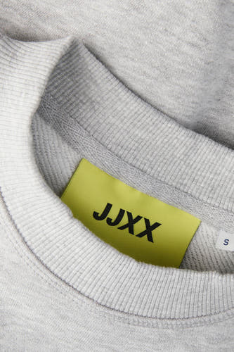 Grijze sweater van JJXX, met een ronde hals en een geel label in de nek.
