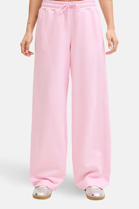Roze joggingbroek van JJXX, met brede pijpen en een trekkoord in de taille, gedragen met zilveren sneakers.

