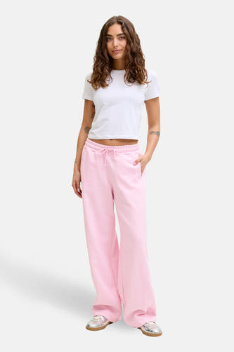 Roze joggingbroek van JJXX, met wijde pijpen en een trekkoord in de taille, gedragen met een wit T-shirt en zilveren schoenen.
