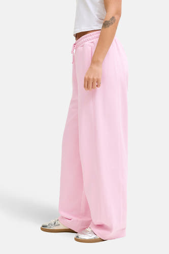 Pantalon de jogging rose de JJXX à jambes larges avec des baskets argentées.