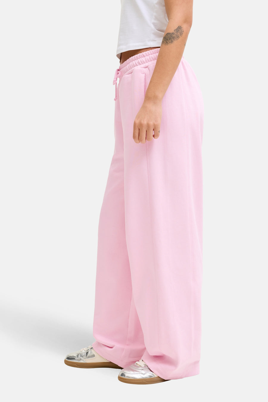 Pantalon de jogging rose de JJXX à jambes larges avec des baskets argentées.