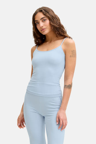 Haut bleu à fines bretelles de JJXX, avec des tatouages subtils sur les bras.