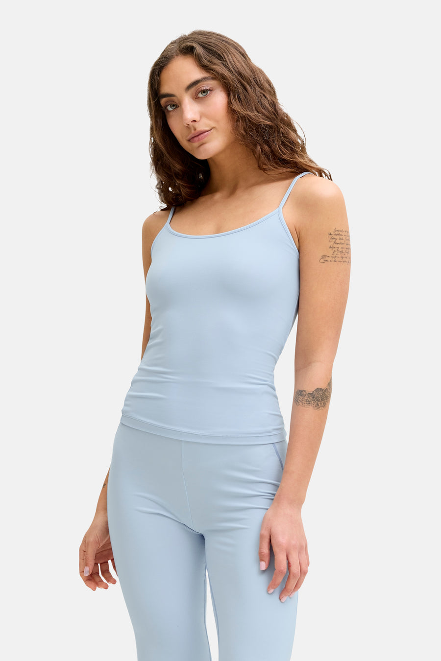 Haut bleu à fines bretelles de JJXX, avec des tatouages subtils sur les bras.