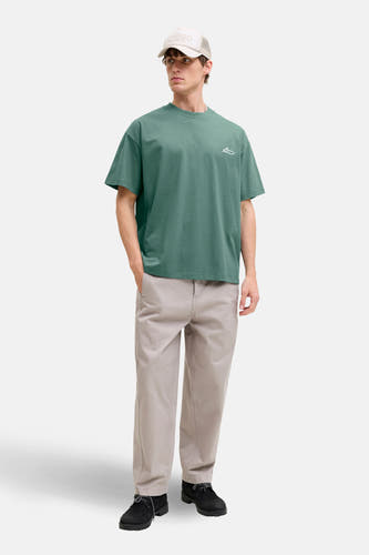 Groen T-shirt met korte mouwen van CORE BY JACK & JONES, met een kleine print, gecombineerd met kaki broek en een pet.

