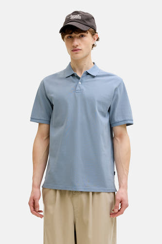 Polo bleu de PREMIUM BLUE by JACK & JONES, porté avec une veste marron et un pantalon beige.