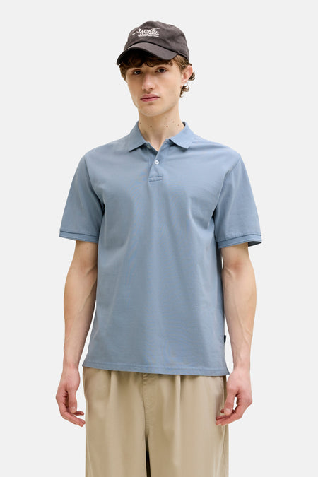 Polo bleu de PREMIUM BLUE by JACK & JONES, porté avec une veste marron et un pantalon beige.