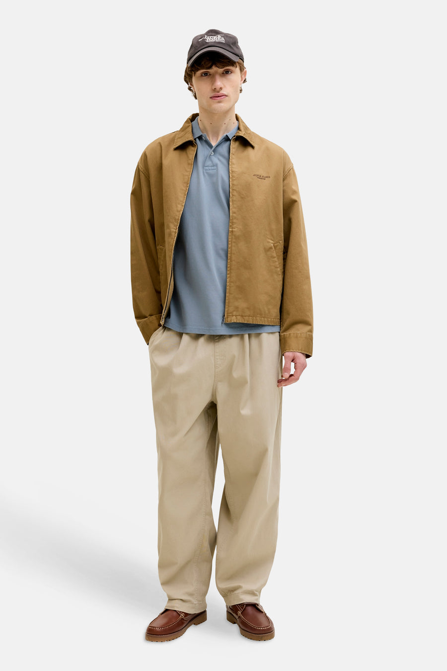Blauw poloshirt van PREMIUM BLUE by JACK & JONES, gedragen met een bruine jas en beige broek.
