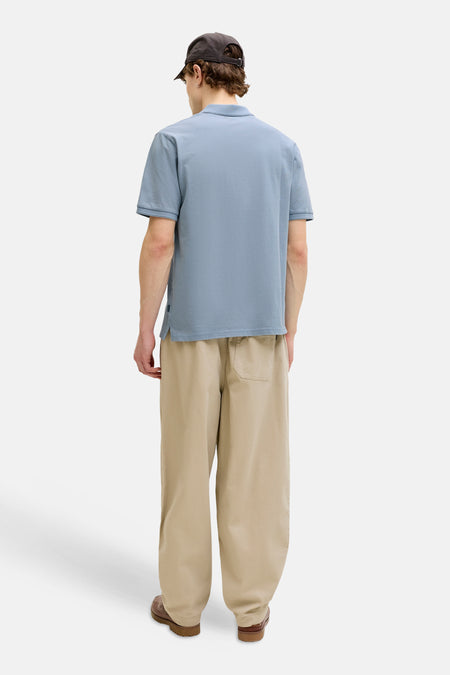 Polo bleu de PREMIUM BLUE by JACK & JONES, vue de dos, avec pantalon kaki et chaussures marron.