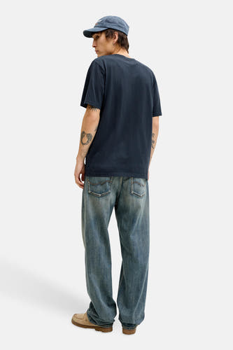 T-shirt bleu à manches courtes de PREMIUM BLUE by JACK & JONES, sur un mannequin, avec casquette bleue et jean ample.