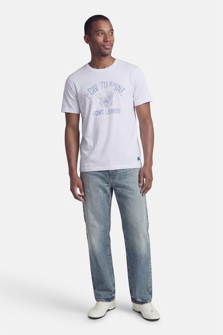 T-shirt blanc de PREMIUM BLUE by JACK & JONES, avec imprimé texte bleu sur le devant, combiné avec un jean bleu et des baskets blanches.