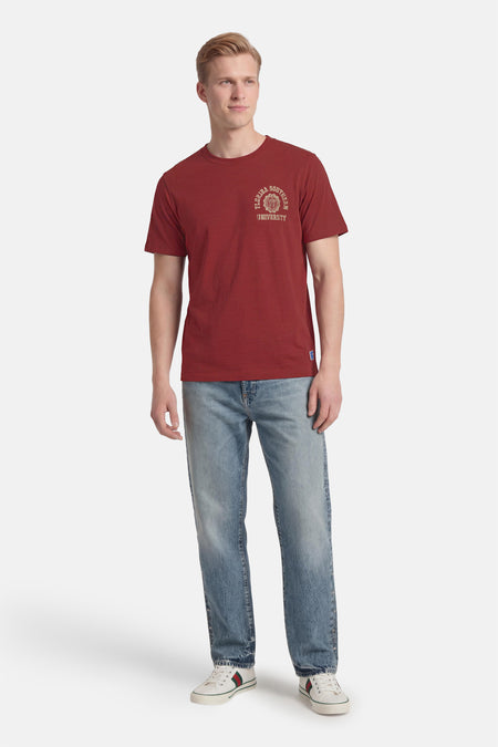 Rood T-shirt van PREMIUM BLUE by JACK & JONES, met een vintage universiteitslogo en gecombineerd met jeans en witte sneakers.
