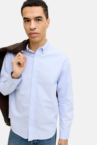 Chemise bleue à manches longues de PREMIUM BLUE by JACK & JONES, avec une veste marron sur l'épaule.