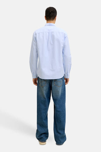 Chemise bleue à manches longues de PREMIUM BLUE by JACK & JONES, avec fermeture boutonnée et portée avec un jean ample.