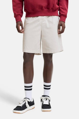 Short beige de JACK & JONES JEANS INTELLIGENCE, porté avec un sweat-shirt rouge, des chaussettes rayées et des baskets noires.