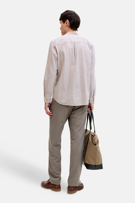 Chino gris de PREMIUM by JACK & JONES, combiné avec des bottes marron et un sac en toile avec détails en cuir, vu de dos.