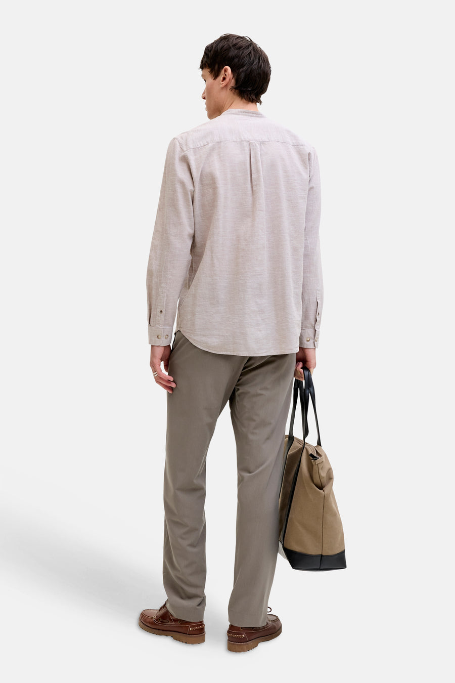 Chino gris de PREMIUM by JACK & JONES, combiné avec des bottes marron et un sac en toile avec détails en cuir, vu de dos.
