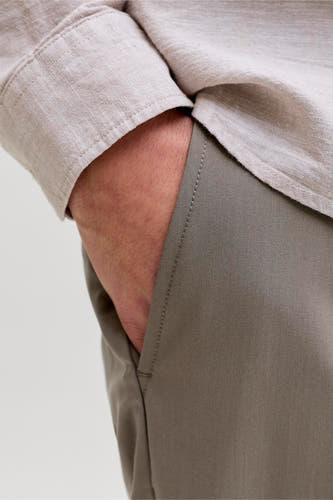 Chino gris de PREMIUM by JACK & JONES, avec poche latérale et main visible.