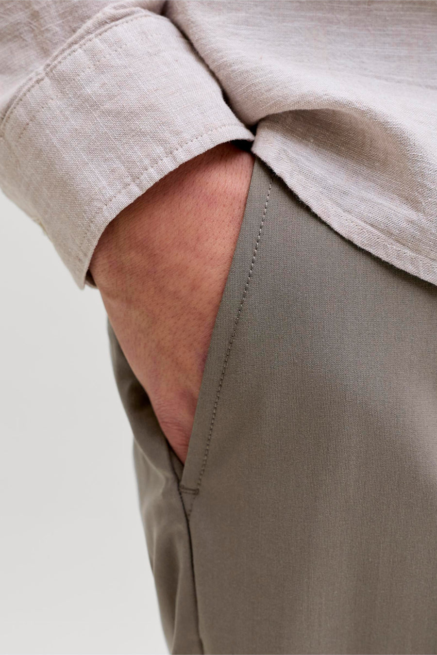 Chino gris de PREMIUM by JACK & JONES, avec poche latérale et main visible.