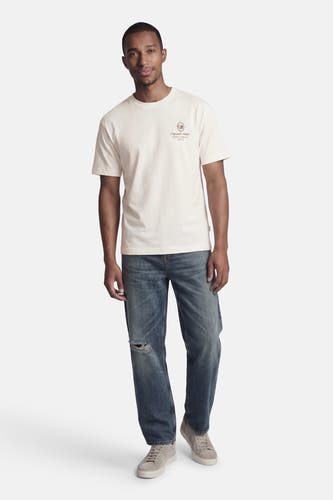 Wit T-shirt met korte mouwen van Originals by Jack & Jones, met klein logo op de borst, gecombineerd met blauwe jeans en grijze sneakers.