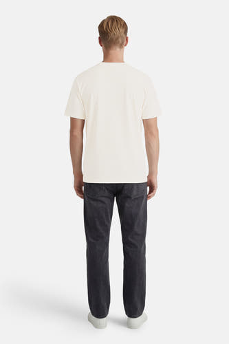 T-shirt blanc à manches courtes de ORIGINALS BY JACK & JONES, porté par un homme en jean foncé et baskets blanches, vu de dos.